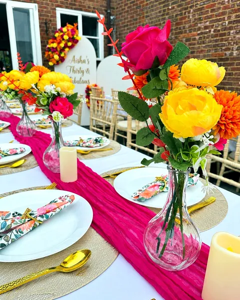 Vibrant pink, orange and yellow floral table arrangements styled for a celebration